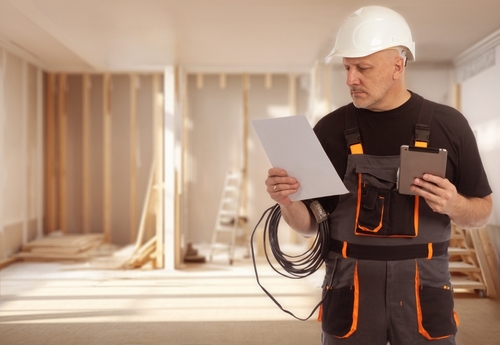 Electrical contractor working on wiring systems inside a building under construction as part of an electrification upgrade.