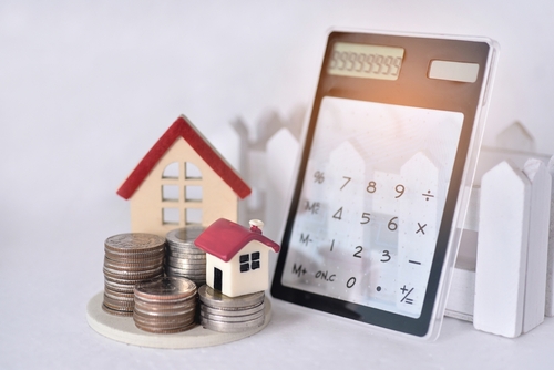 Calculator with model houses and stacked coins illustrating mortgage rates today March 2026 and home affordability
