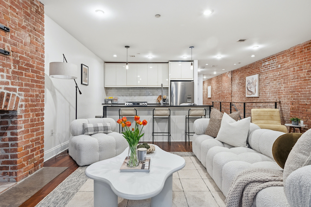 Harlem brownstone duplex condo interior featuring exposed brick walls, open kitchen with breakfast bar, and modern living area with contemporary furnishings